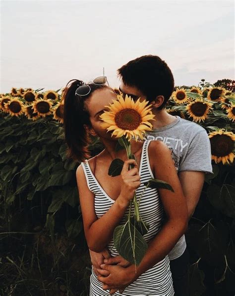 A Man And Woman Kissing In Front Of A Field Of Sunflowers