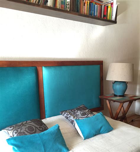 A Bed With Blue Headboard And Pillows In A Room Next To A Book Shelf