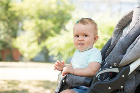 Little Girl Sitting In The Pram Baby Looking At Camera Nature