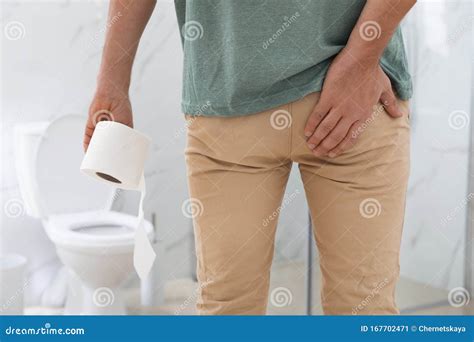 Boy With Paper Suffering From Hemorrhoid On Toilet Bowl In Rest Room