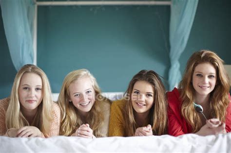 Portrait Of Four Teenage Girls Lying On Bed — Fun Posing Stock Photo