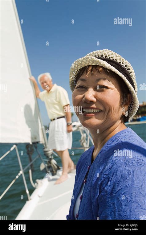 Woman Smiling On Sailboat Husband In Background Portrait Stock Photo