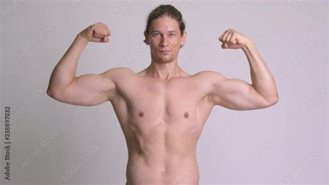Handsome Muscular Man Flexing Biceps Shirtless Against White Background