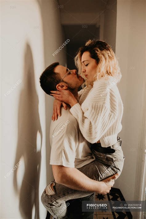 Passionate man and woman embracing and kissing at wall at home — young man, casual - Stock Photo ...