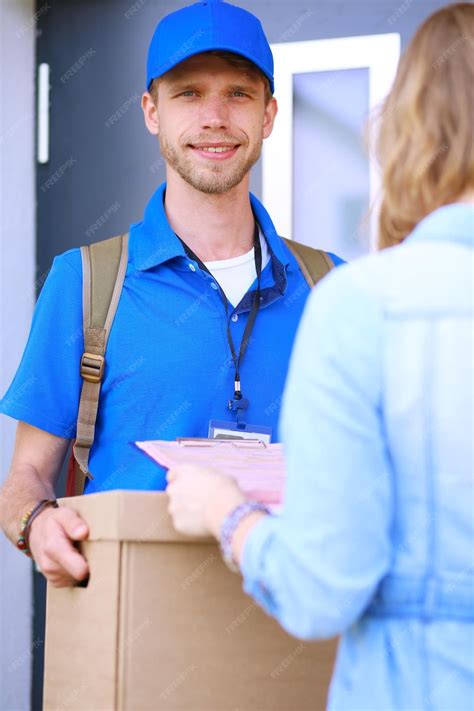 Premium Photo Smiling Delivery Man In Blue Uniform Delivering Parcel