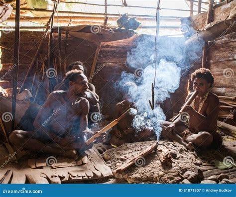 Familia De La Tribu De Korowai Que Se Sienta Por El Fuego En Una Casa