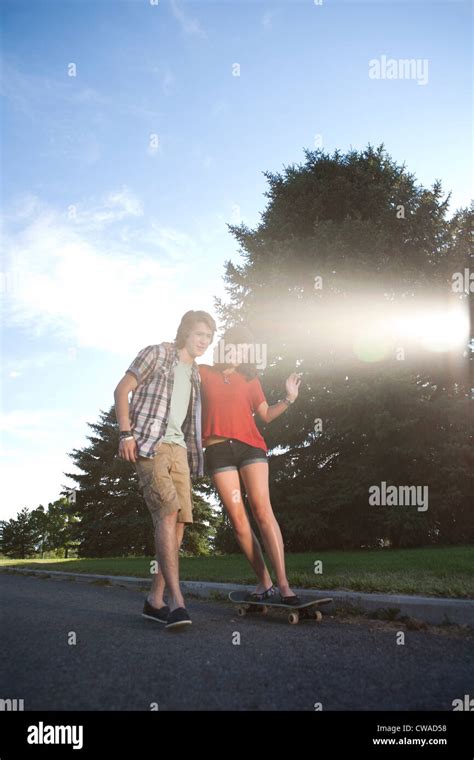 Teenage Boy Helping Girlfriend Ride Skateboard Stock Photo Alamy