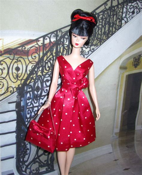 A Barbie Doll Dressed In A Red Polka Dot Dress And Carrying A Purse On The Stairs