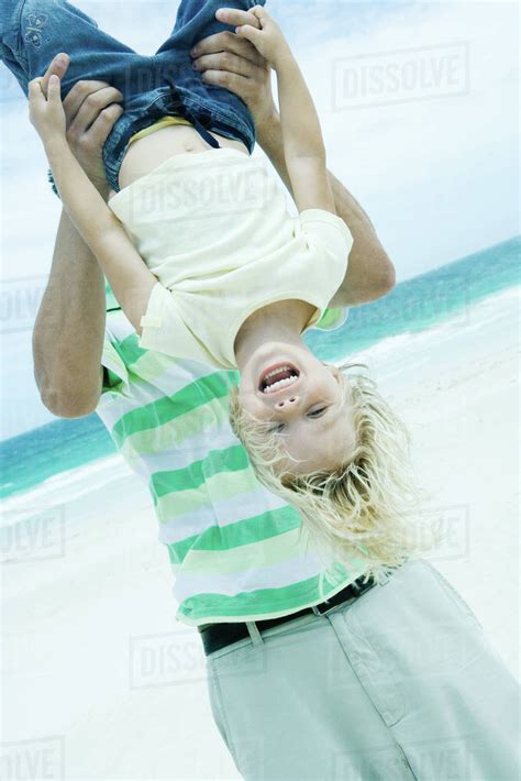 Man Holding Child Upside Down On Beach Stock Photo Dissolve