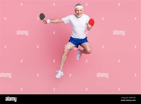 full length body size photo senior man jumping up playing ping pong with rackets isolated pastel
