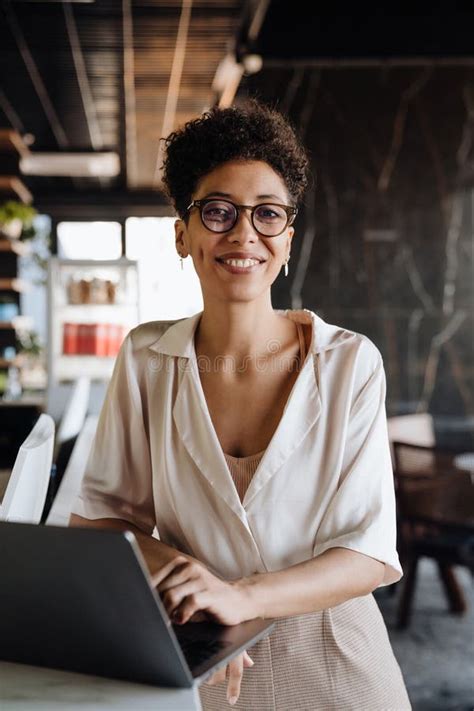 Happy Black Businesswoman Smiling And Using Laptop In Office Lobby