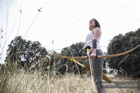 Female Archer With Bow And Arrow Standing On Meadow — Sky Shooting