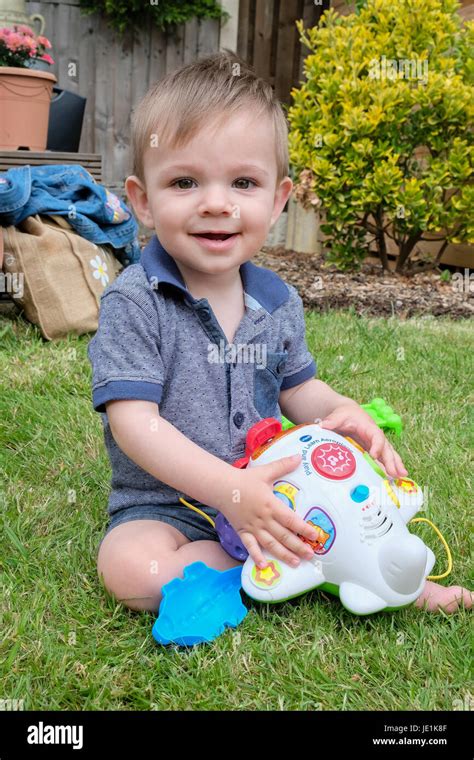 Baby Boy Sat On Grass In Garden Playing Stock Photo Alamy