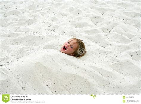 The Head Of A Funny Little Girl Sticking Out Of The Sand