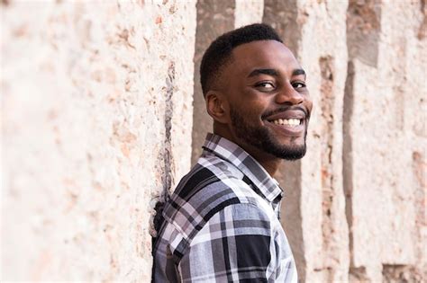 Premium Photo Portrait Of Smiling Young Man Leaning Against Wall