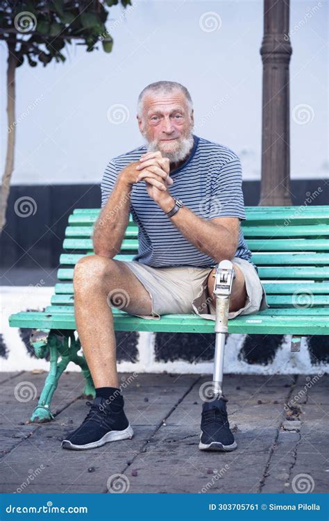 Elderly Man With Prosthetic Leg Left Rests Sitting On A Park Bench