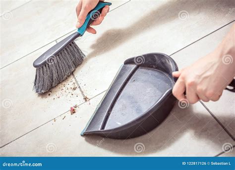 Female Hands Sweeping Dust With A Broom On A Dustpan Housekeeping