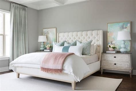A Cream Tufted Headboard With White Bedding And Blue Pillows Provides A