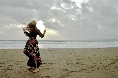 Lady In A Formal Floral Patterned Dress On A Dramatic Grey Windy Beach