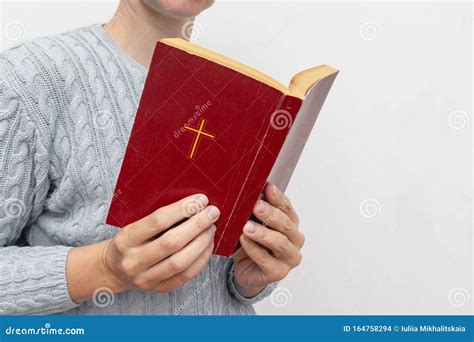 Young Praying Christian Woman`s Hands Holding Holy Bible With A Cross