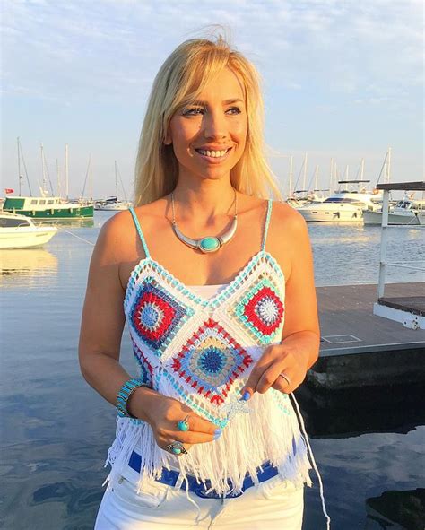 A Woman Standing In Front Of A Body Of Water Wearing White Shorts And A Crocheted Top