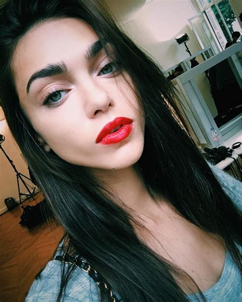 A Woman With Long Black Hair And Red Lipstick On Her Face Is Posing For