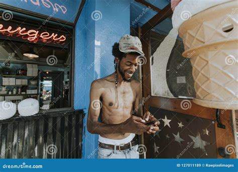 Shirtless Man Playing On His Phone Outside A Restaurant Stock Image