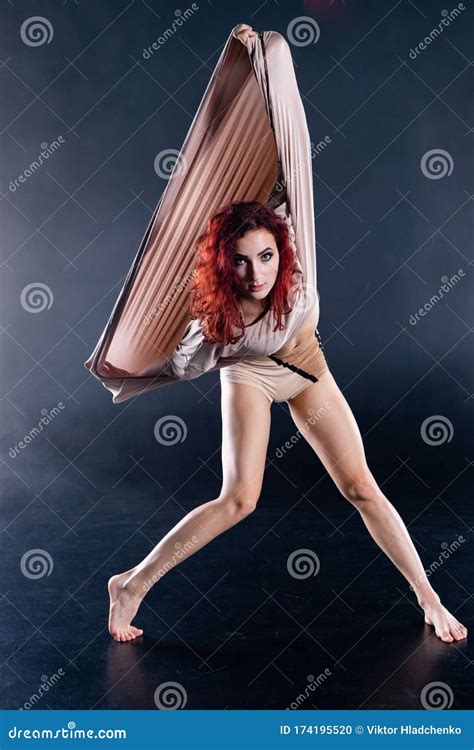 female athletic and flexible aerial circus artist with redhead dancing in the air on the silk
