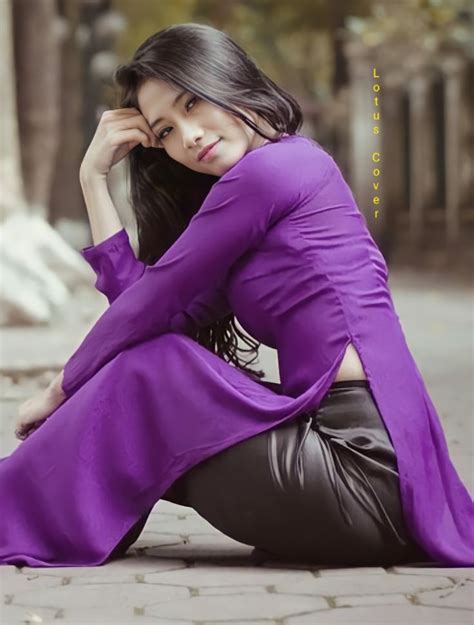 A Woman Sitting On The Ground Wearing A Purple Shirt And Black Leather Pants With Her Hands In