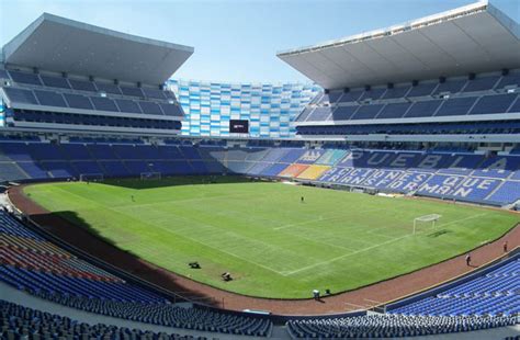 White shirt with a blue strip, crossing from upper right to. Estadio Cuauhtemoc