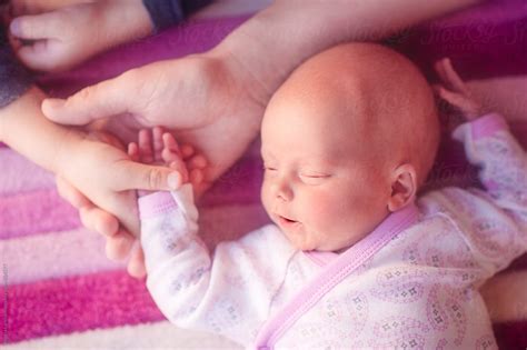 Close Up Of Hands A Newborn Girl With Her Hand Being Held By Her