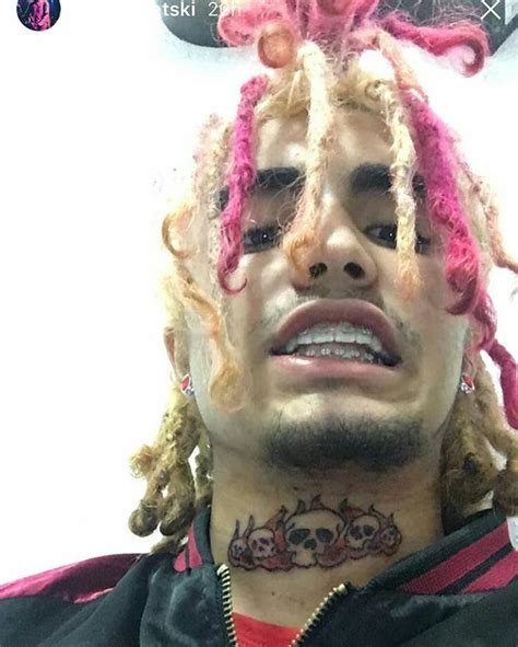 a man with pink dreadlocks and tattoos on his face