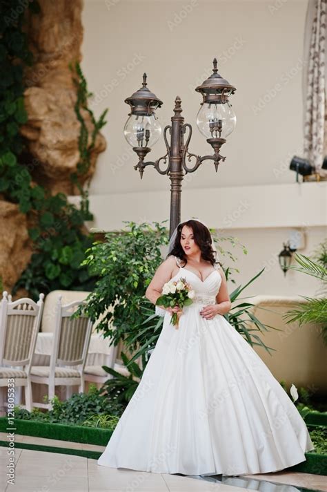 big breasts brunette bride with wedding bouquet posed at wedding hall background lantern stock