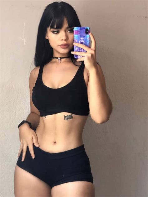 a woman taking a selfie with her cell phone while wearing black shorts and a crop top
