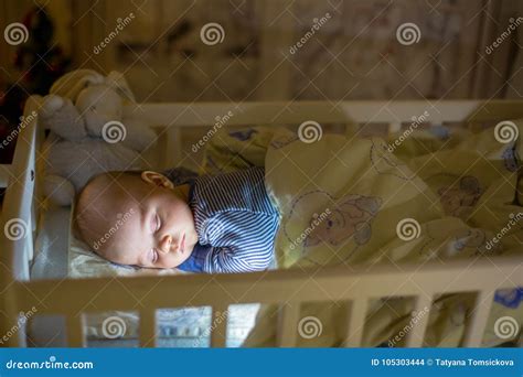 Adorable Newborn Baby Boy Sleeping In Crib At Night Stock Photo