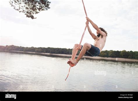 Young Man Rope Swinging Above Lake Stock Photo Alamy