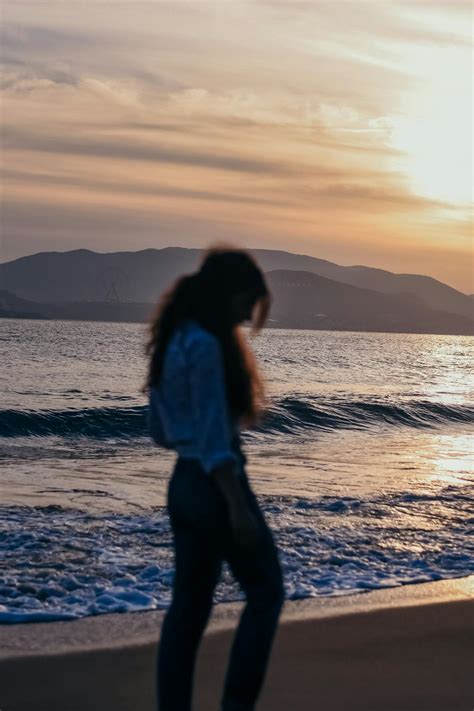 Woman Standing On Seashore During Sunset · Free Stock Photo