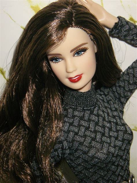 A Close Up Of A Doll With Long Hair Wearing A Sweater And Holding A Purse