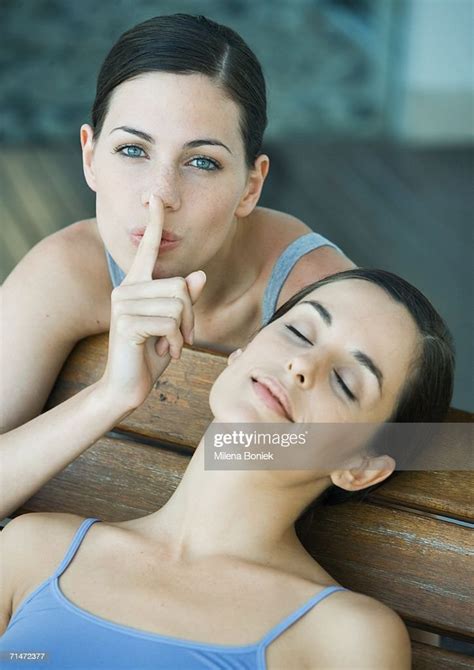 Young Woman With Finger On Lips While Her Friend Is Sleeping Portrait