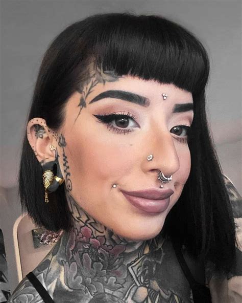 A Woman With Tattoos And Piercings On Her Face