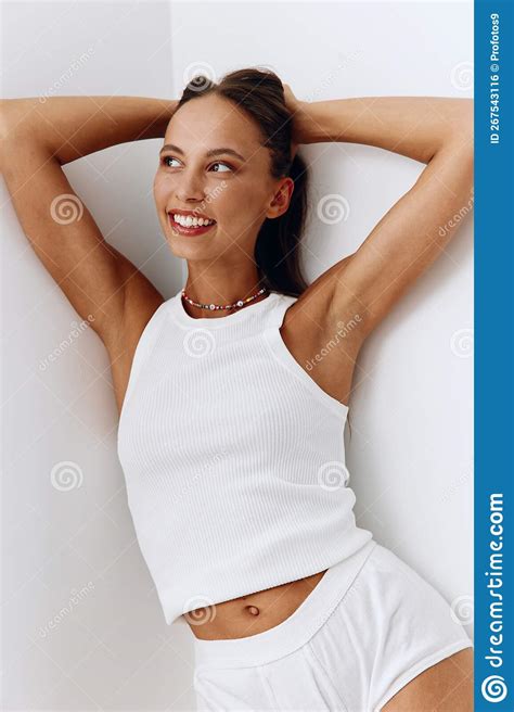 A Woman With A Beautiful Body And Tanned Skin Poses In The White Corner