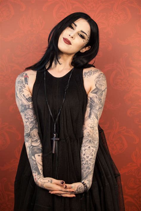 A Woman With Black Hair And Tattoos On Her Arm Wearing A Black Dress