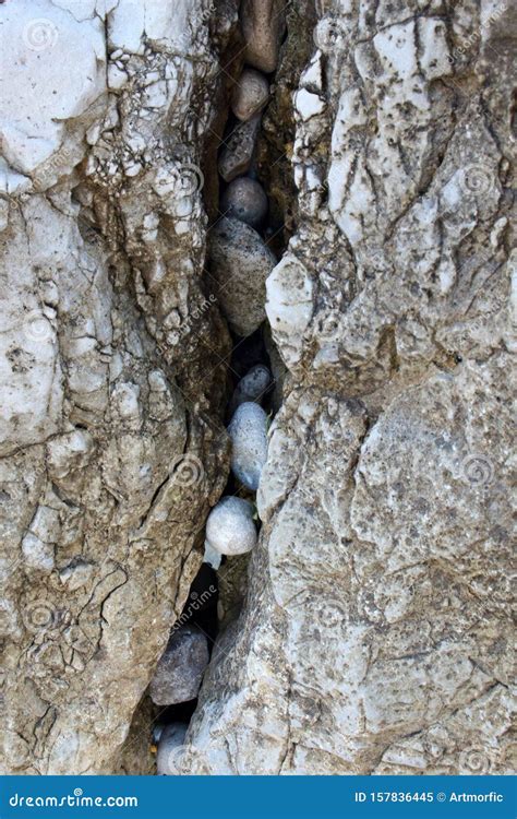 Small Beach Pebbles Stones Stuck In A Crack Between Two Big Rocks