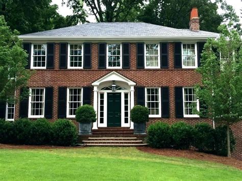 Classic red brick colonial house in the winter, with snow in the front yard, pine trees, a cleared black top driveway, and a bright, day time blue sky background. house shutter colors for red brick | Brick exterior house ...