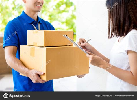 Woman Signing Document Receiving Parcel Box From Delivery Man Stock