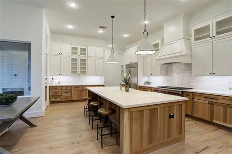 A Large Kitchen With Wooden Floors And White Cabinets An Island