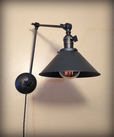 An Old Fashioned Wall Light With A Black Shade On Its Arm And The Bulb