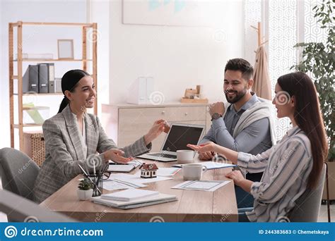Real Estate Agent Giving House Key To Young Couple In Office Mortgage Concept Stock Image