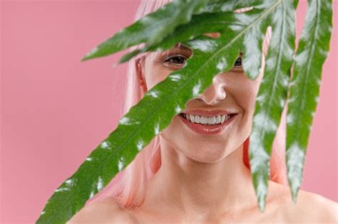 Premium Photo Portrait Of Happy Woman With Pink Hair Smiling At Camera Hiding Behind Green