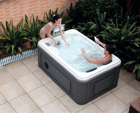 Two People In A Large Hot Tub With Plants Around The Edges And One
